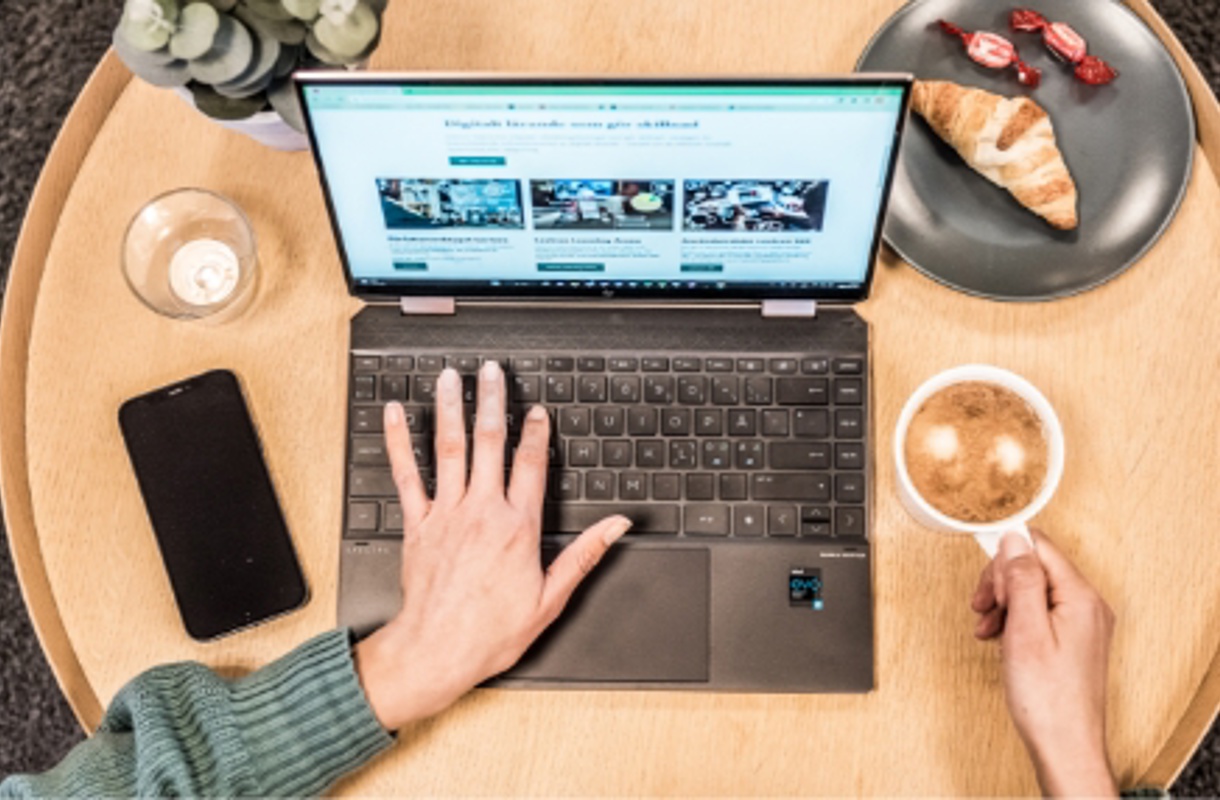 Skriver på laptop med en kopp kaffe bredvid